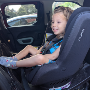 Image shows a small girl, who has SMA, in a car seat in the car.