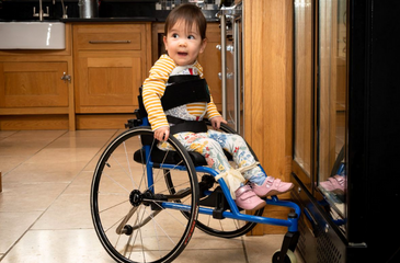 Image shows young girl who has SMA, sitting in her wheelchair.