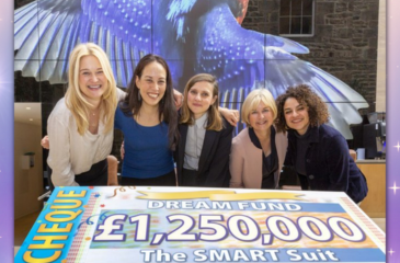 Image shows 5 female adults crowded round a large cheque showing the amount awarded to the SMART Suit project.