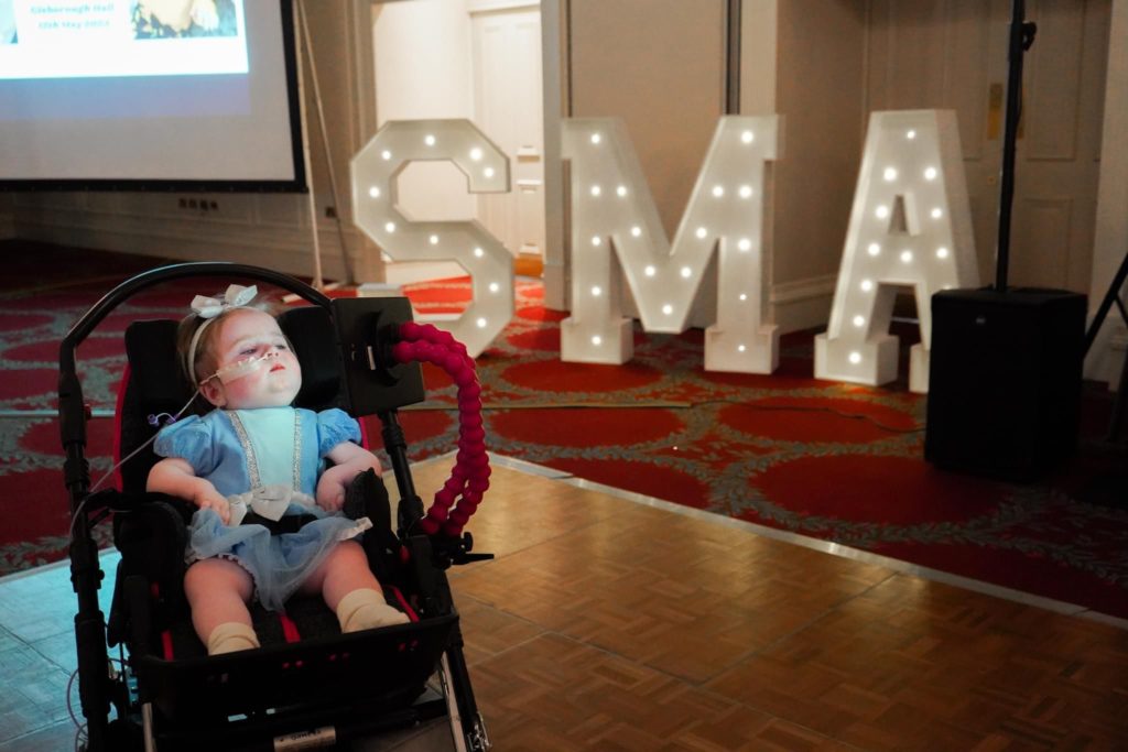 One year old girl with SMA with a party background