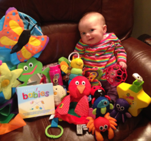 Image shows a baby with SMA Type 1 with toys from SMA UK's multisensory toypack.