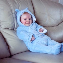 Infant in blue sat on sofa