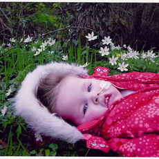 Toddler in red coat lying on grass