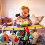 Image shows a young child with SMA Type 2 in a highchair with a tray, playing with toys.