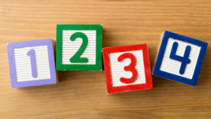 Image shows four multicoloured blocks with numbers on. 