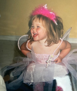 Image shows a young girl with blond hair in a pink fairy costume.