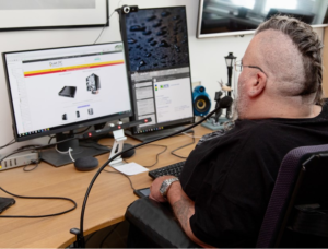 Image shows an adult man using his computer with assistive technology.