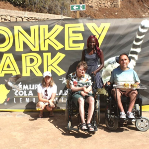 Image shows two men, both wheelchair users, sitting outside a zoo.