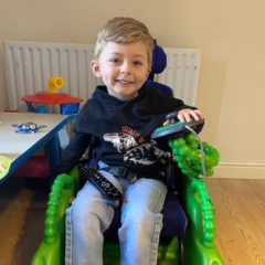 Image shows a young boy who has SMA Type 2, sitting in his Bugzi wheelchair.