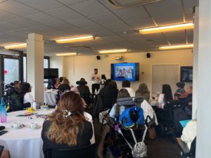 Image shows a group of young people listening to a speaker at the Moving Forward Event