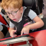young boy with SMA using propped up ipad