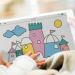 young child's hands exploring picture of castle on tablet