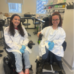 image shows two ladies in powerchairs wearing lab coats