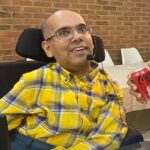 Vik in checked shirt speaking at a meeting