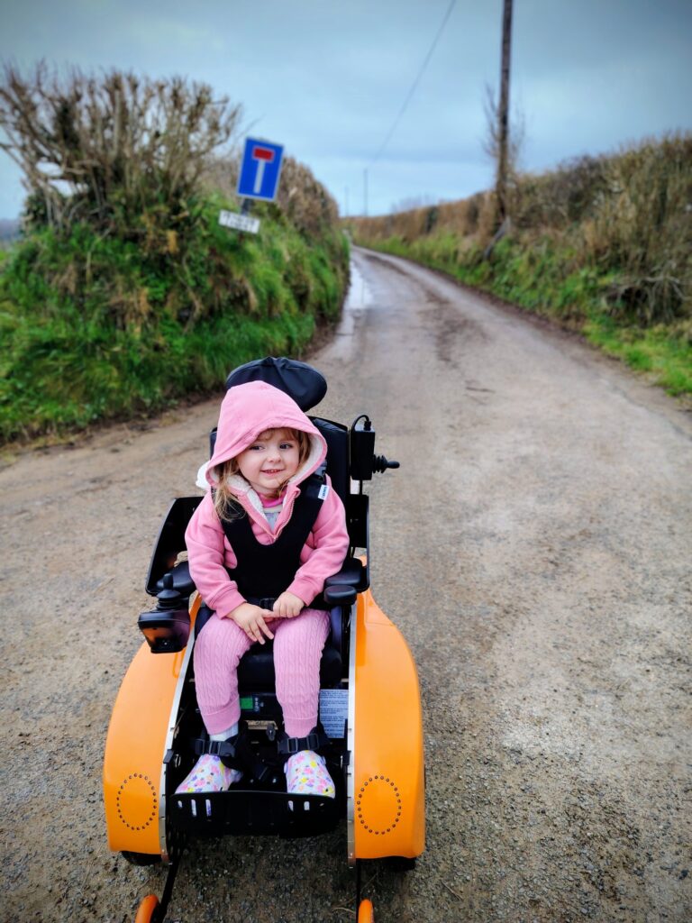 Young girl on a country lane in a bright yellow powered wheelchair